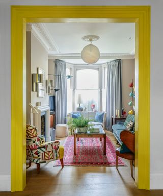 Cream painted living room with bright yellow accent color on entryway, soft blue curtains and accessories