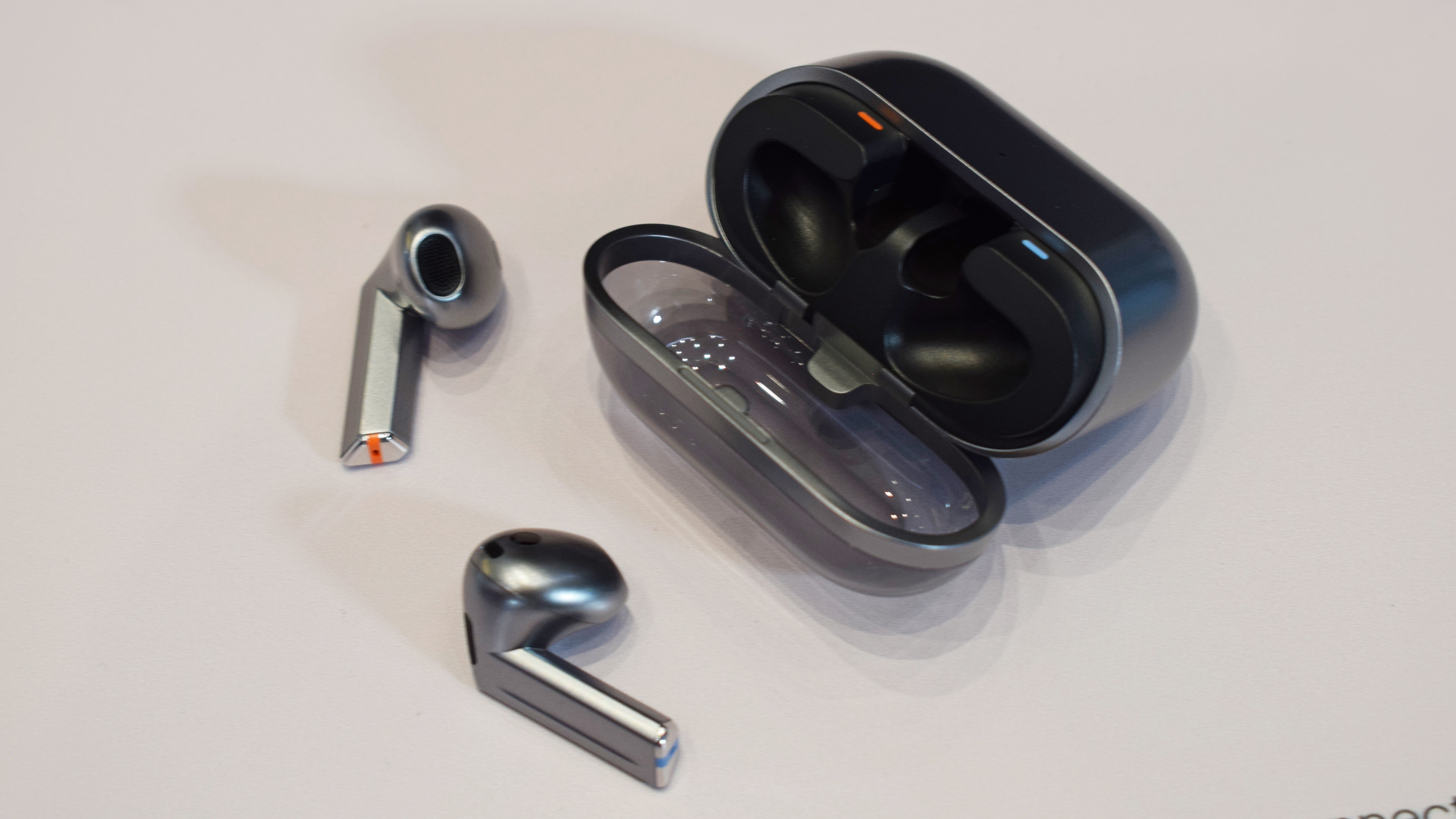 Samsung Galaxy Buds 3 Pro with their case, on a table