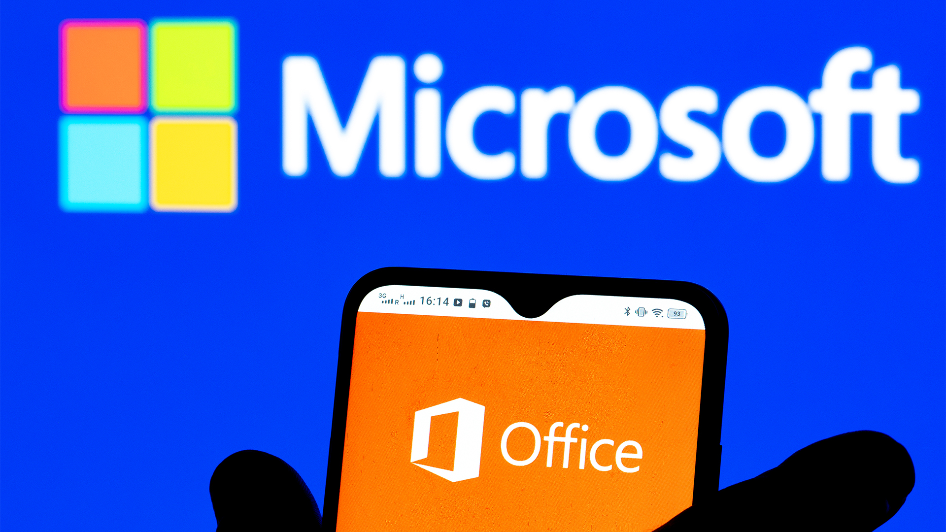 Microsoft Office app logo pictured on a smartphone screen with Microsoft logo and branding in background.