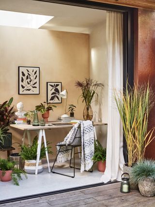 home office next to large open doors with lots of house plants