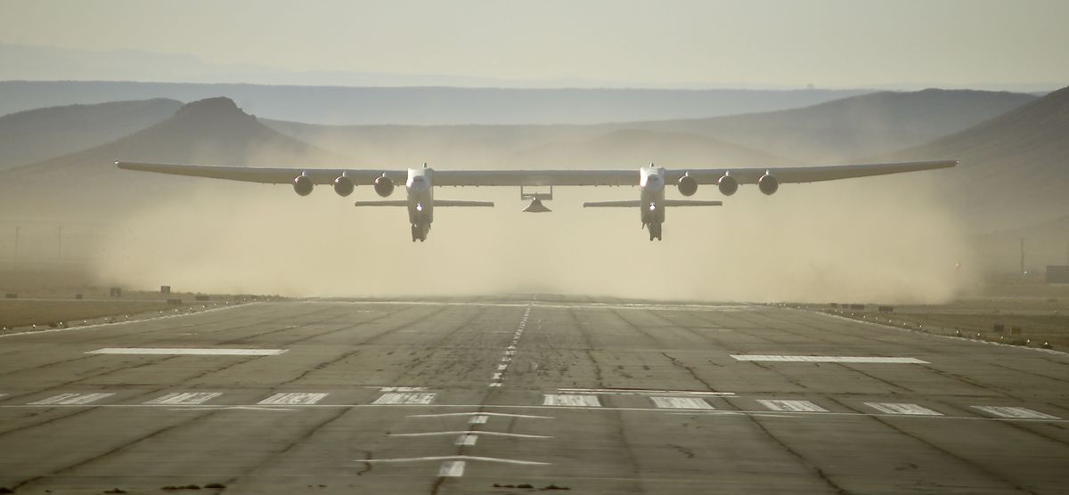 Stratolaunch&#039;s giant carrier plane Roc and its Talon-A testbed above the runway with dust behind