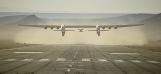 Stratolaunch's giant carrier plane Roc and its Talon-A testbed above the runway with dust behind