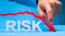 A man's finger is pushing down a red line, as a graph, over the word, "risk."