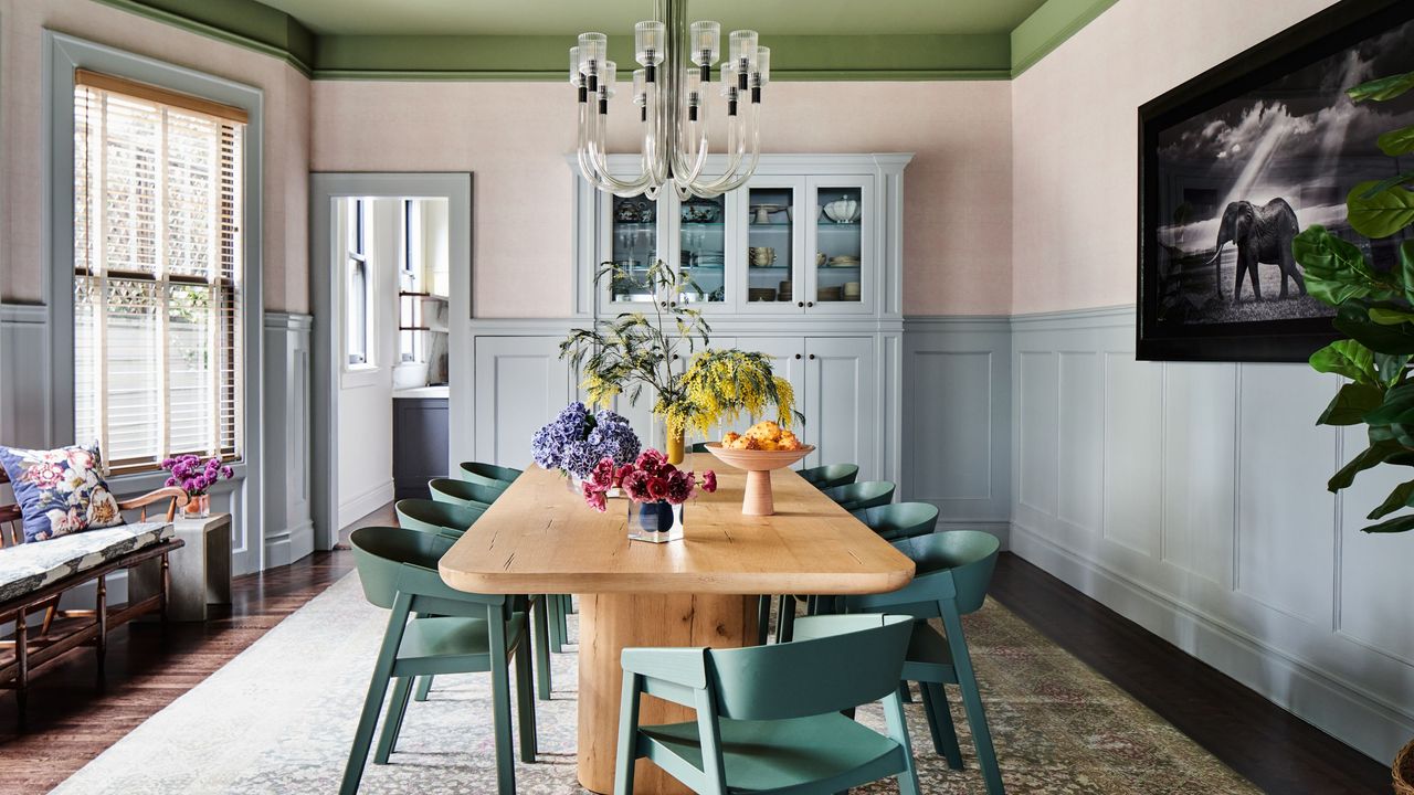colorful San Francisco dining room with a green painted ceiling, light blue half paneled walls, a pine table with green chairs and a sculptural glass chandelier