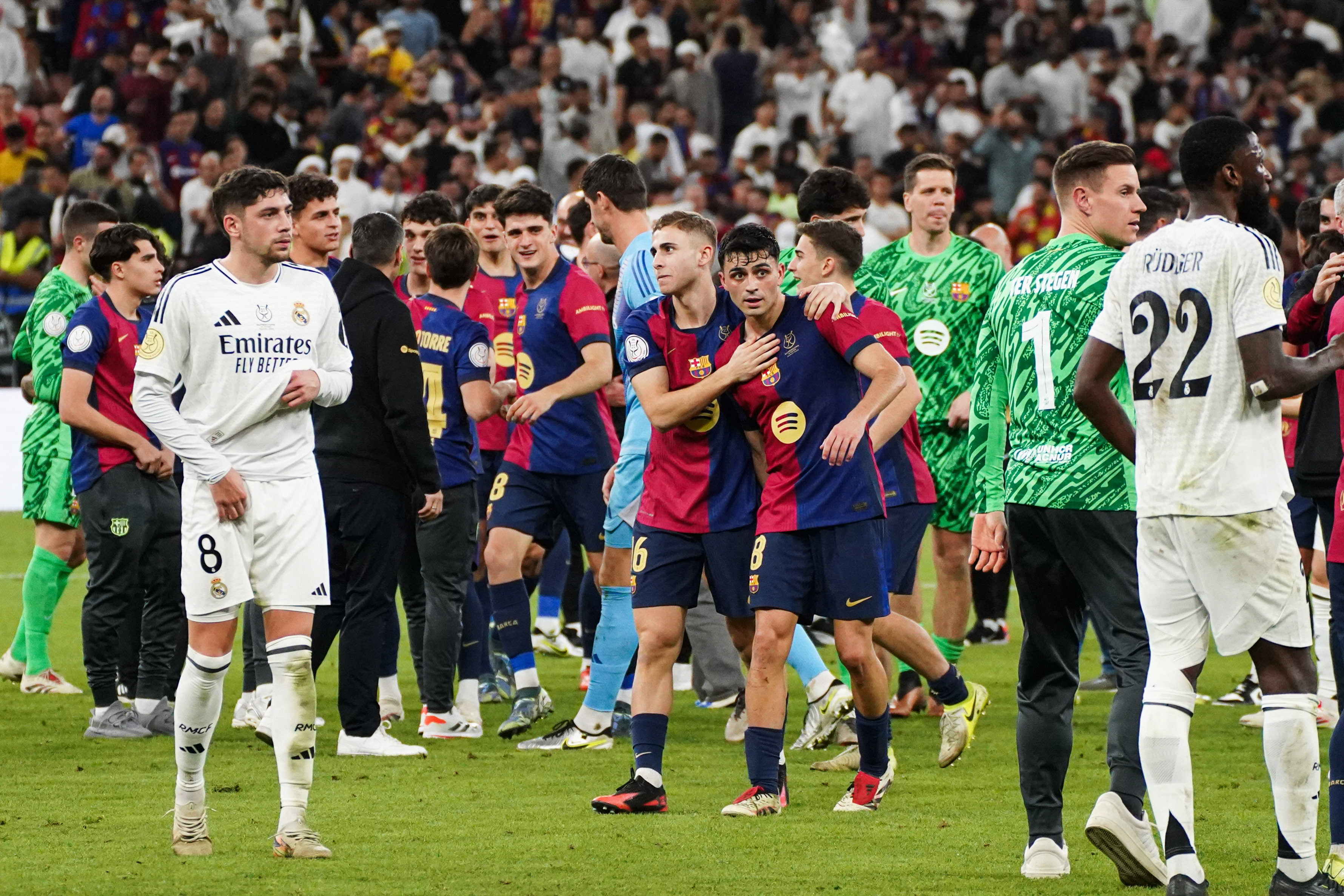 Real Madrid pair Fede Valverde and Antonio Rudiger look dejected as Barcelona players celebrate their Supercopa de España win over Los Blancos in January 2025.