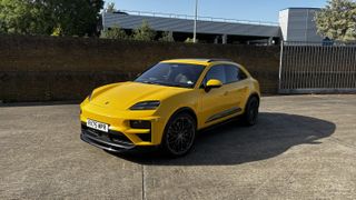A yellow Porsche Macan in a car park in front of a wall