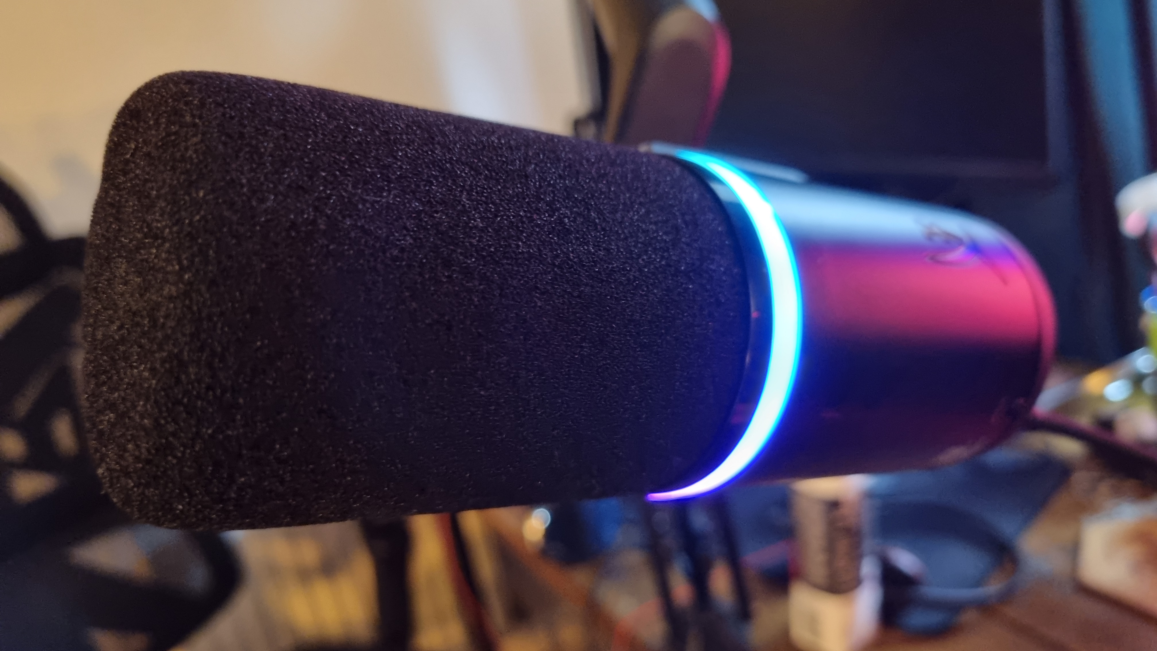 A HyperX FlipCast gaming microphone, with its RGB ring lit up in blue and pink