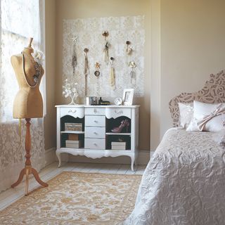 bedroom with white wooden flooring off white walls with jewellery stand and hang hooks with white dressing table
