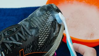 Running shoe being cleaned with a toothbrush