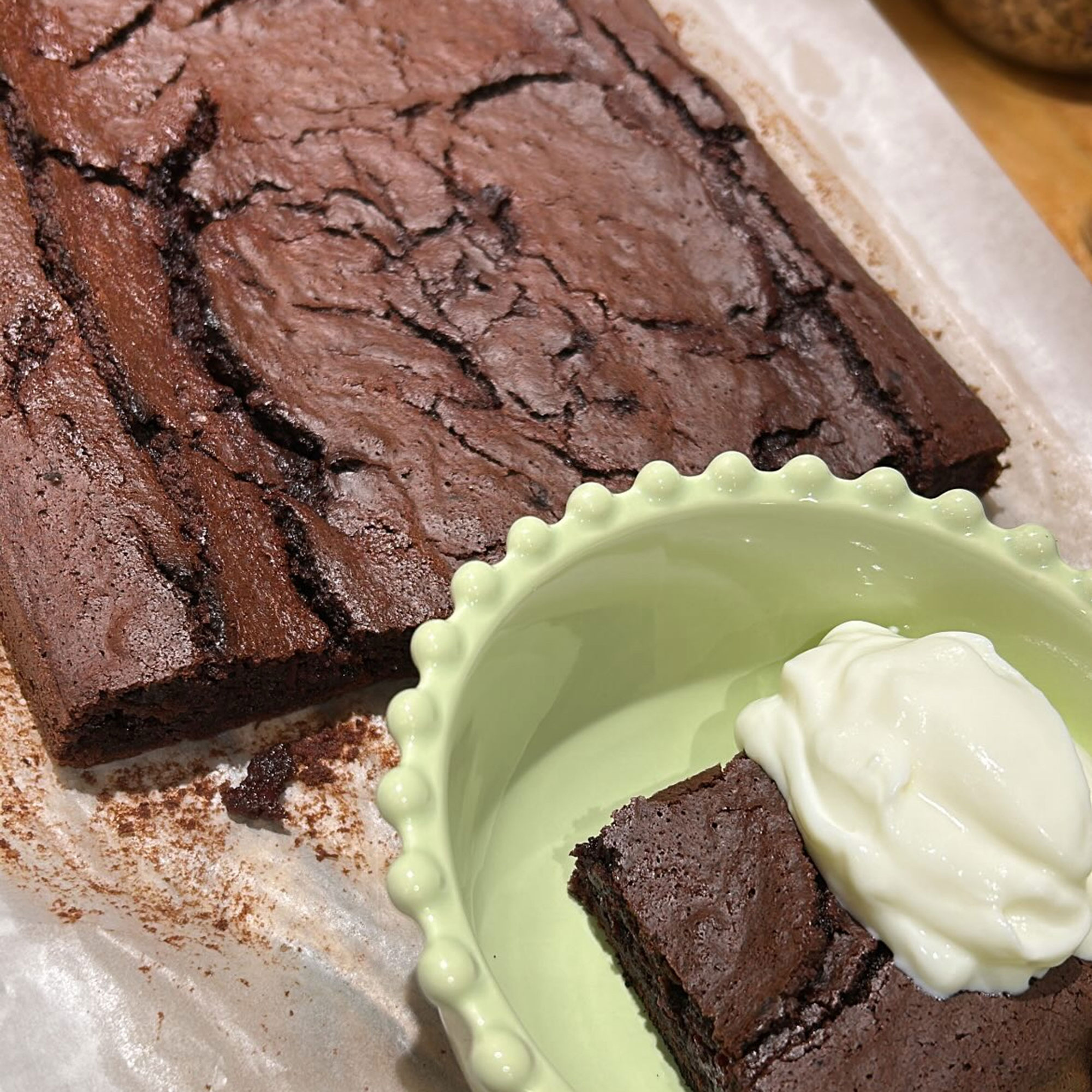 Brownie on pan with a square cut off and placed into green bowl