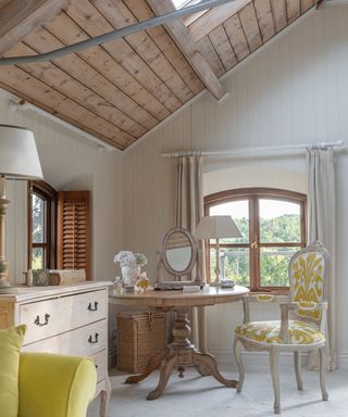 dressing table area in a bedroom with wooden vaulted ceiling and curved windows