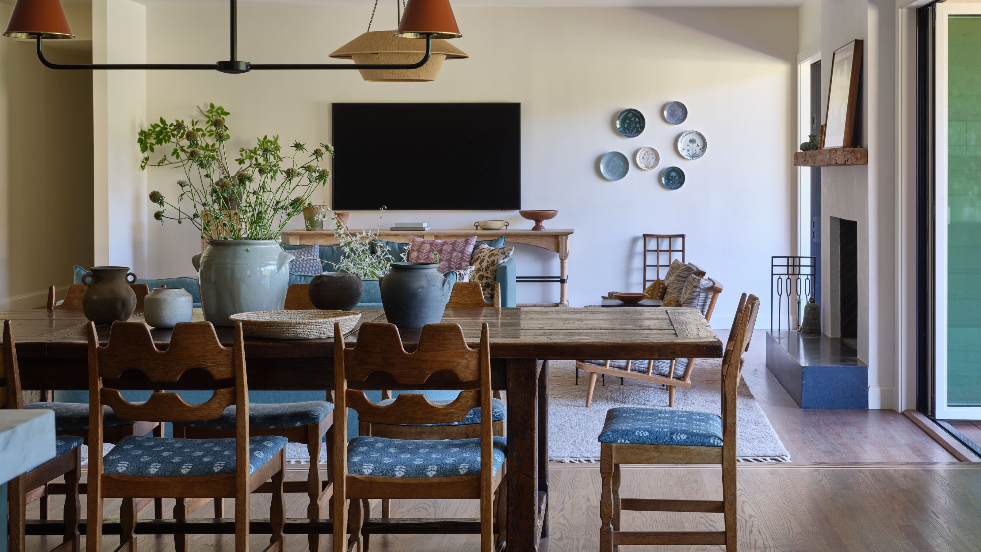 a bright open plan living and dining room with a large wooden table and vintage swedish pine chairs