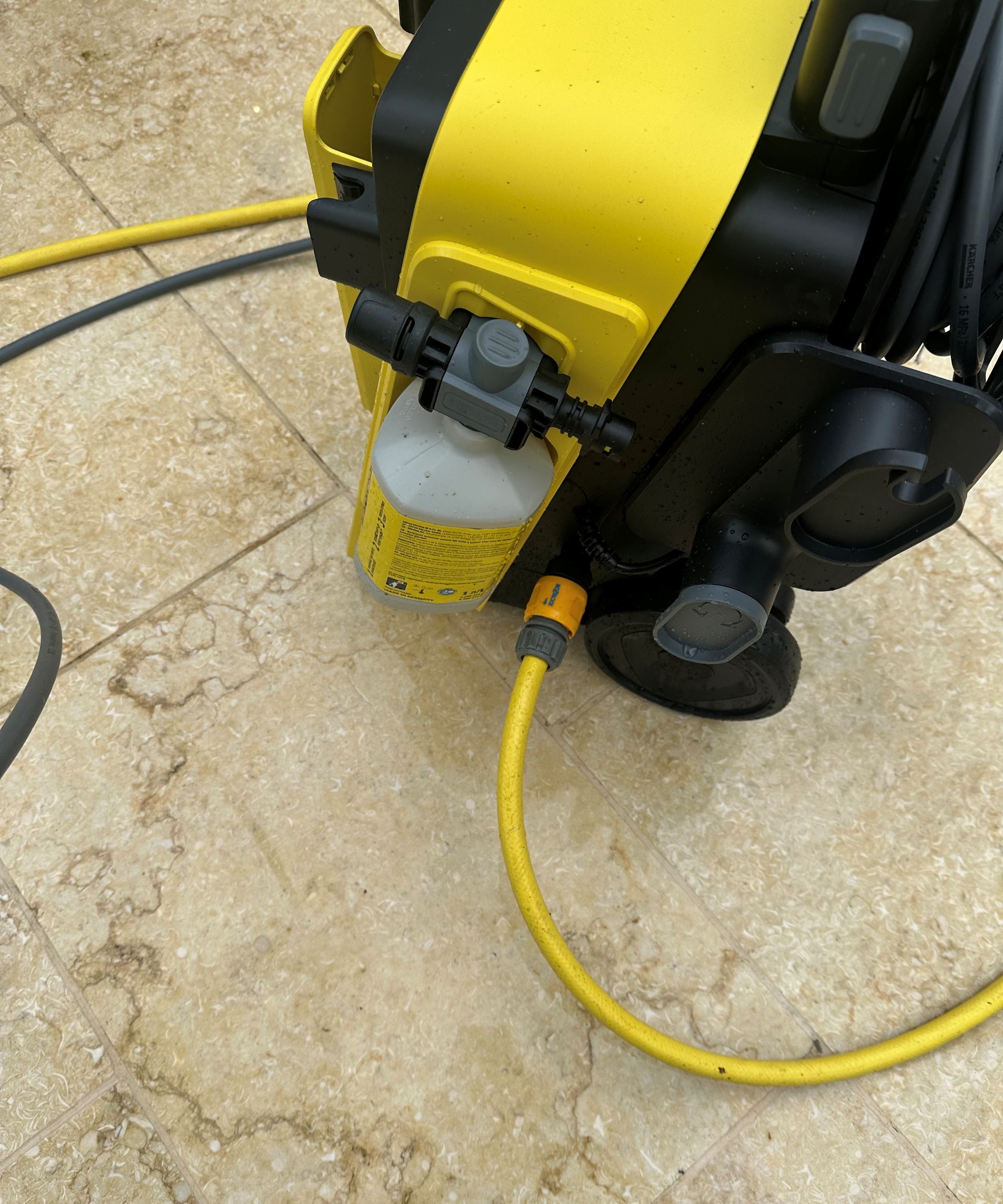 A yellow K&amp;auml;rcher K5 Comfort Premium pressure washer on a cream limestone patio