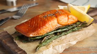 A fillet of salmon which has been cooked in an air fryer with string beans and a lemon wedge