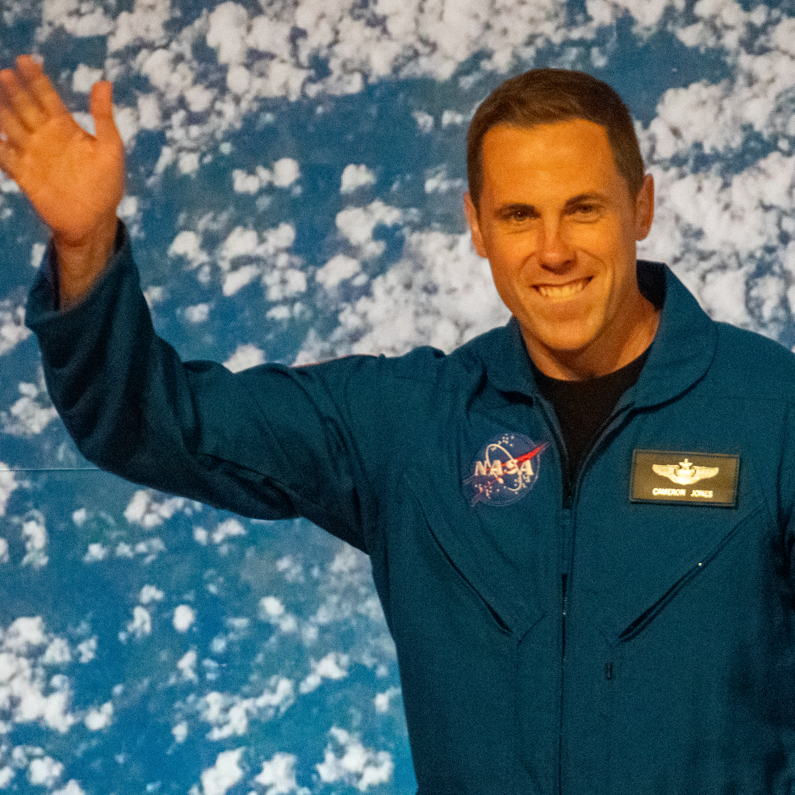 people in blue jumpsuits smile and wave.