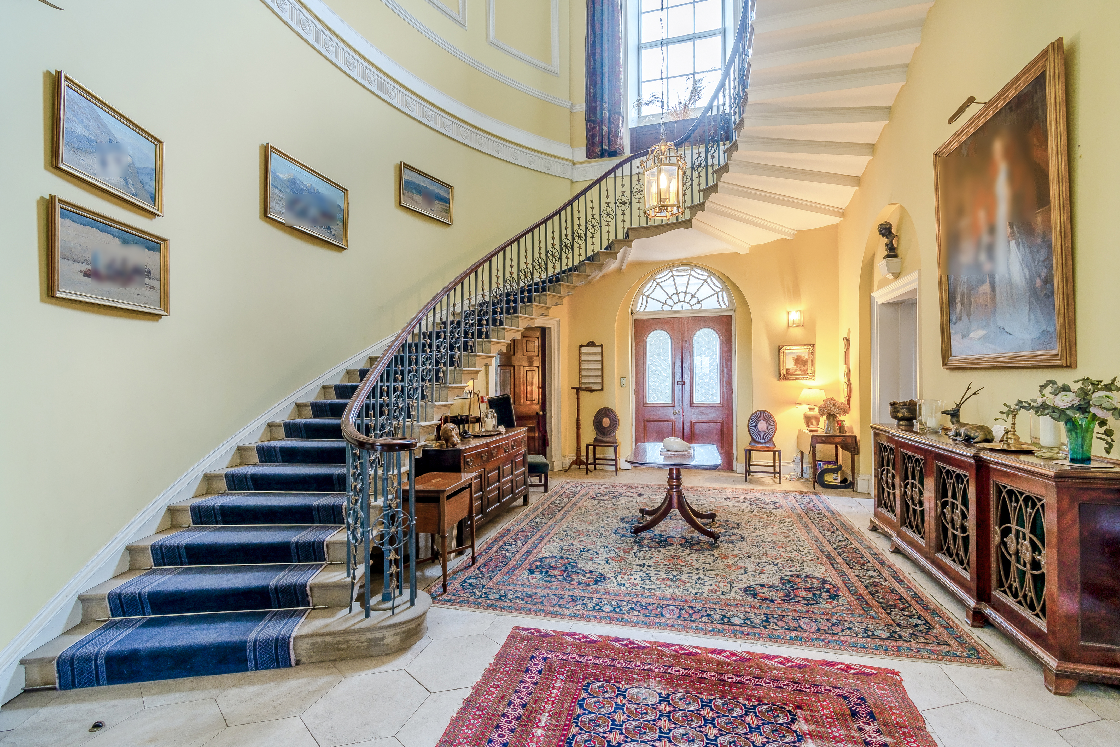 An entrance hall with a large spiral staircase covered in a blue carpet