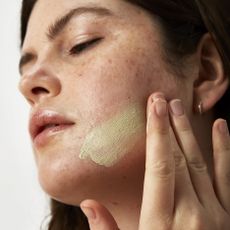 Model applying face mask sold at Cult Beauty