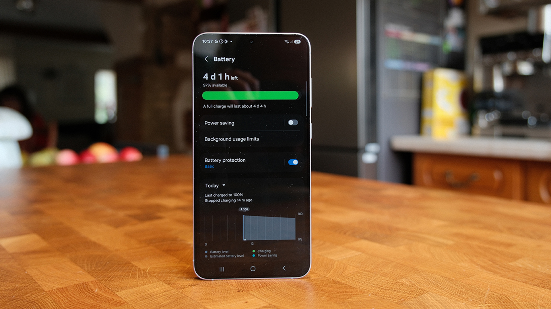 Samsung Galaxy S25 Plus smartphone stood up on wooden table showing battery life on screen