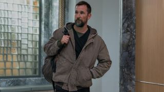 Noah Wyle as Robby walking into The Pitt with a backpack slung on his left shoulder.
