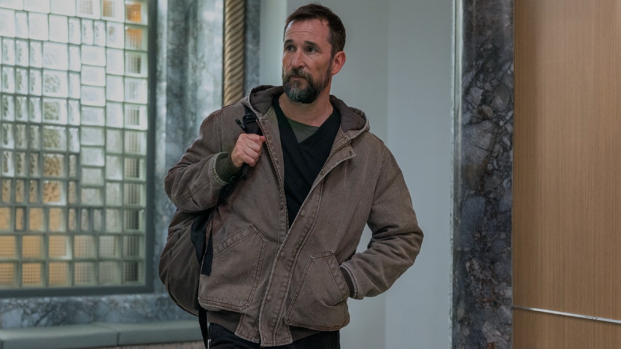 Noah Wyle as Robby walking into The Pitt with a backpack slung on his left shoulder. 