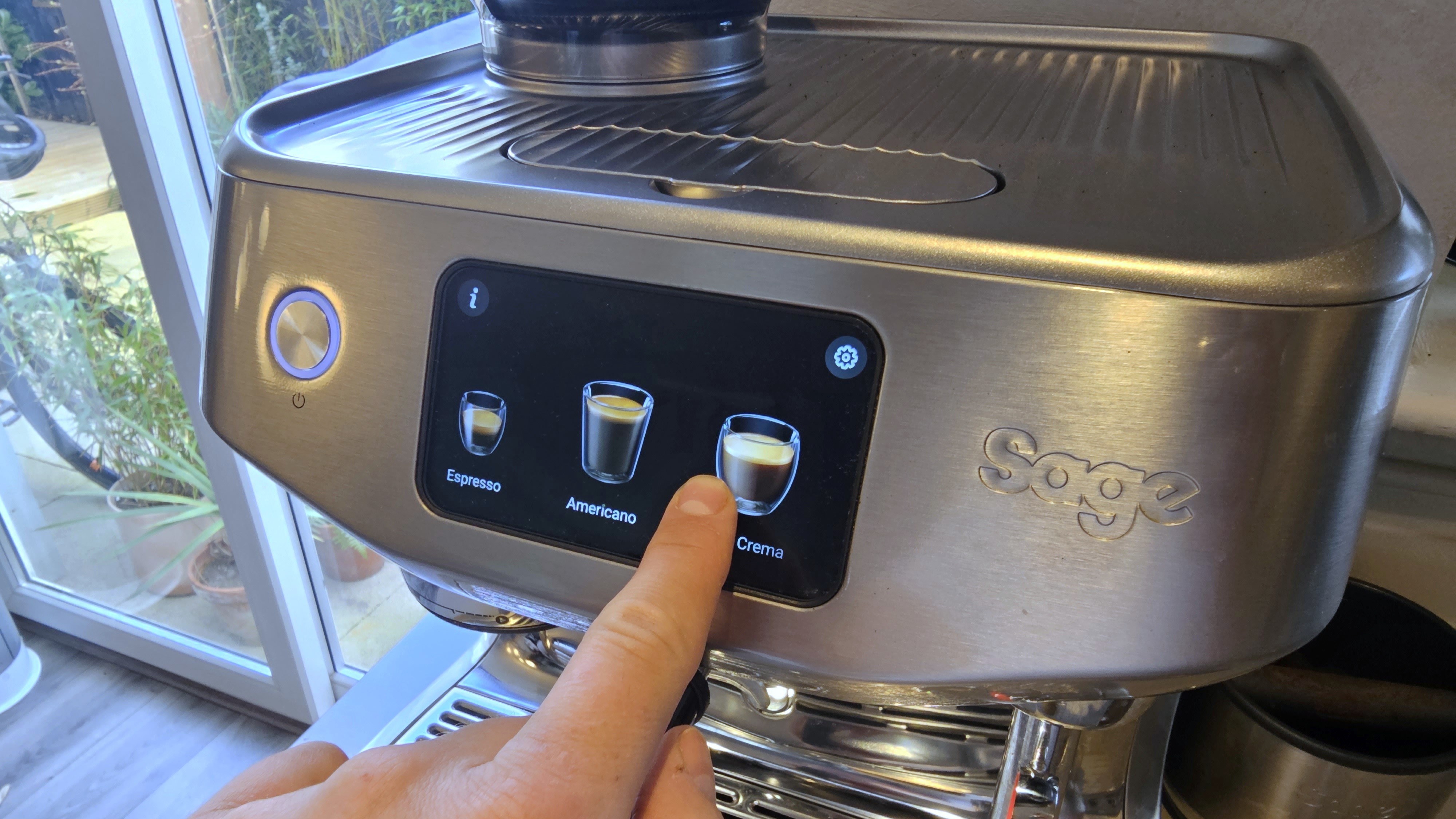 Person using touchscreen control panel on Sage Oracle Jet coffee maker