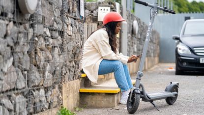 Woman sitting on a step next to a Pure Air electric scooter