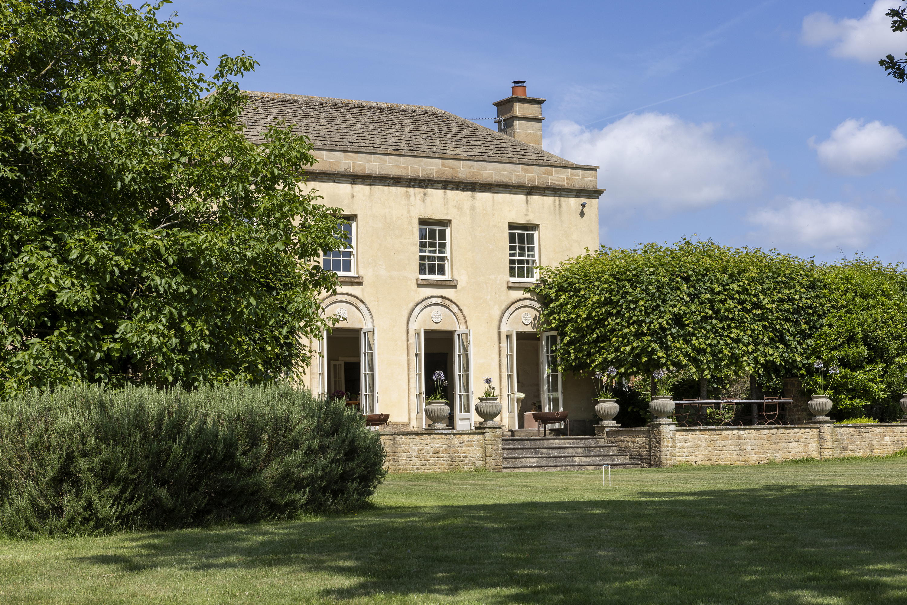 Mount Farm's beige exterior surrounded by trees and bushes