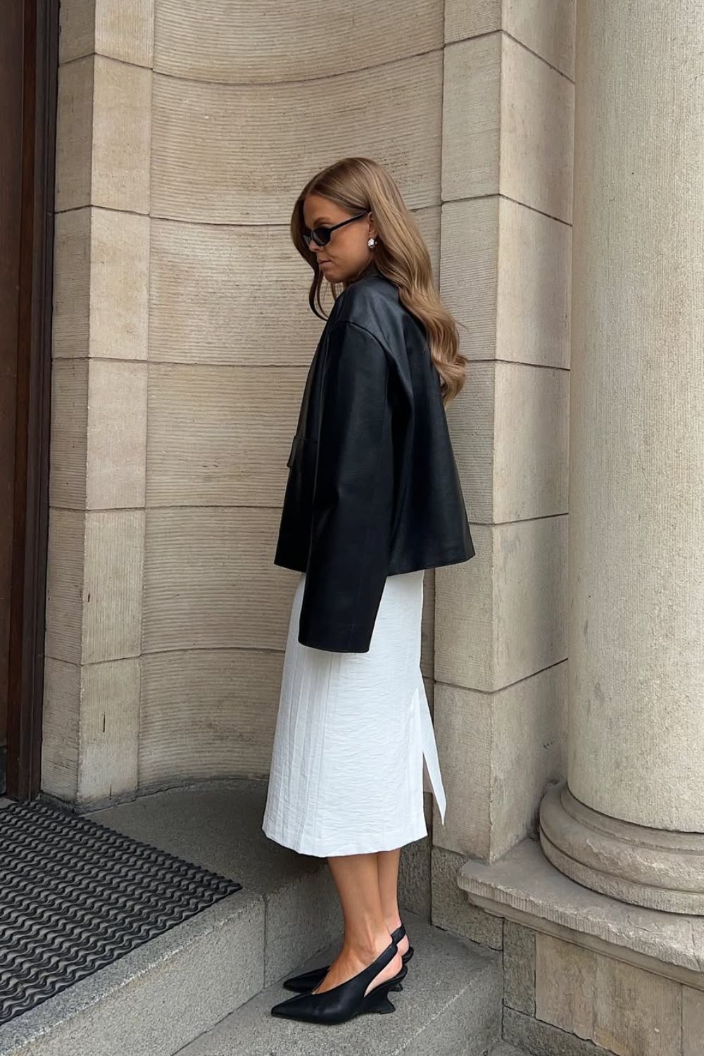 Anti-flat shoes trends winter 2025 @haaannajohansson wearing a black leather jacket, white skirt and black wedge slingback courts