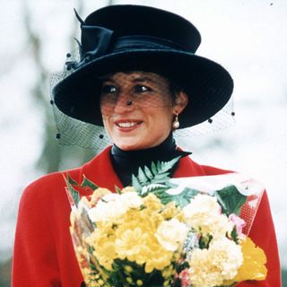 Princess Diana wearing a red coat and black hat holding flowers