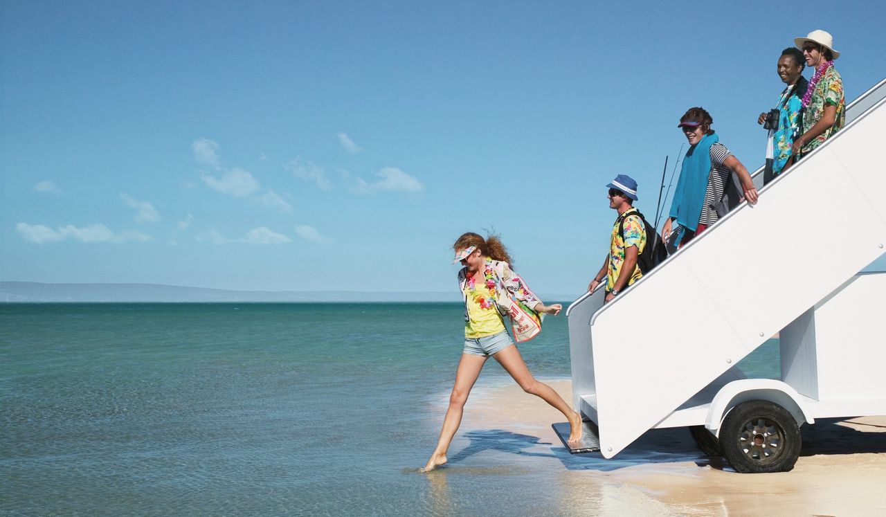 Five people descending aeroplane stairs into sea, side view