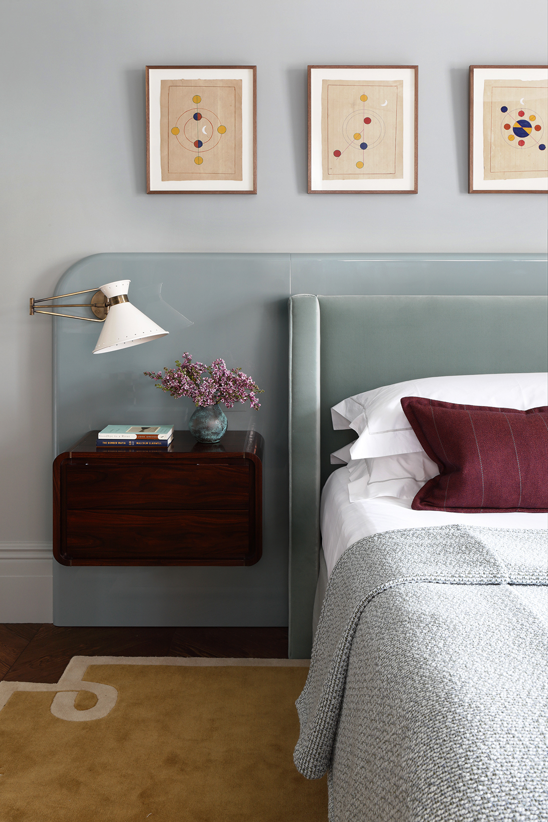 A bedroom with subtle blue walls, a glossy blue backboard and a light blue chenille headboard