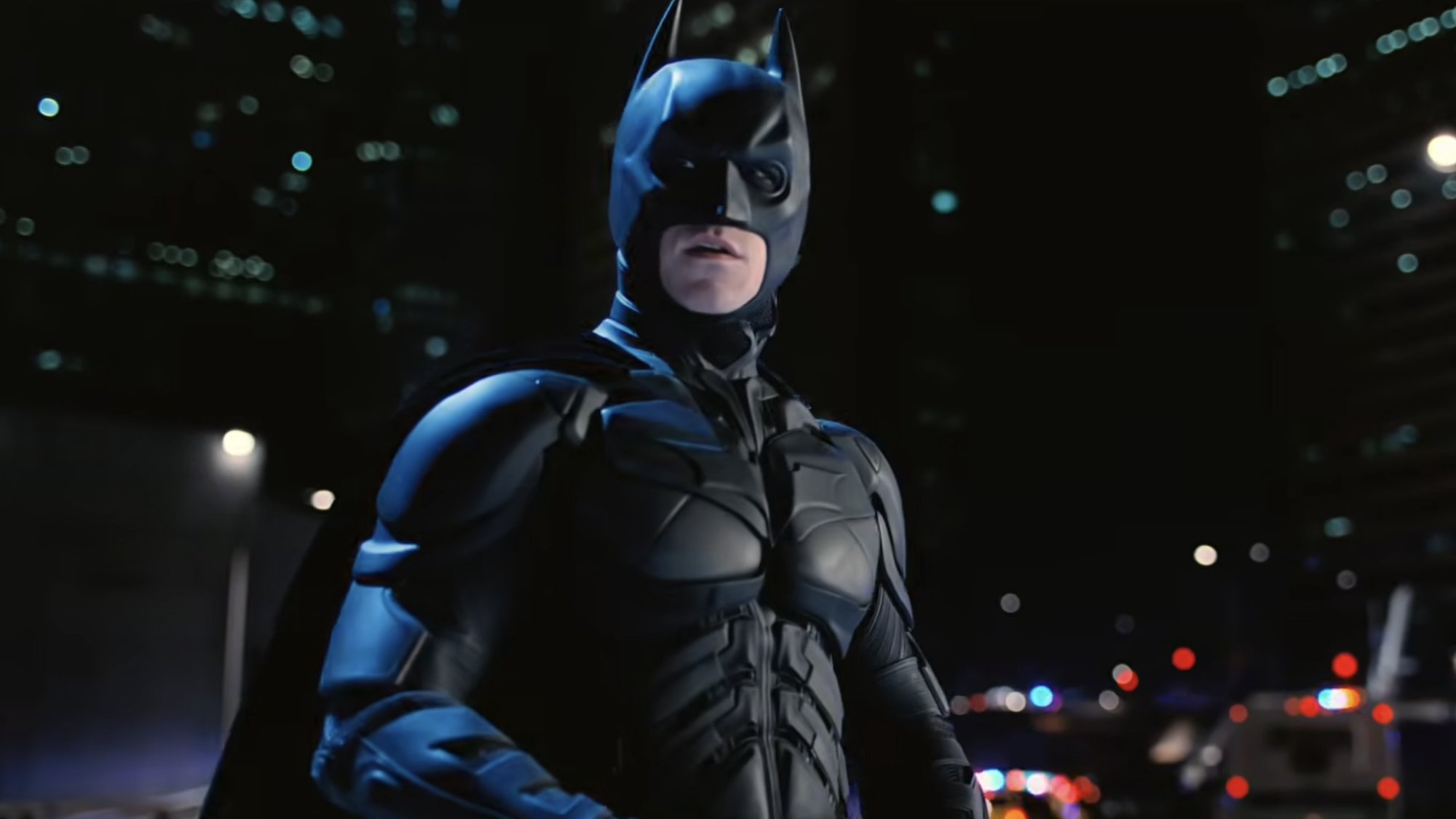 Batman (Christian Bale) looks over across Gotham City as police pursue him in The Dark Knight Rises.