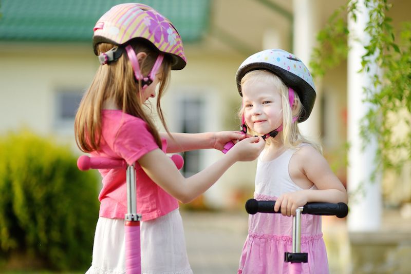 Girls putting on bike helmets