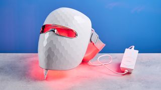 the ulike reglow led skincare mask showing its red LED light and control and charger