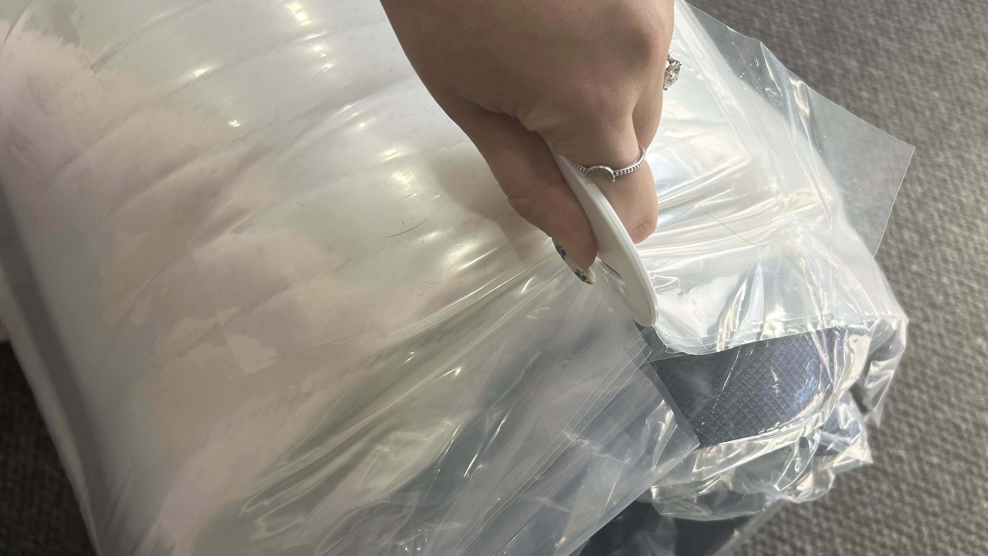 Hand holding cutter on mattress plastic wrap