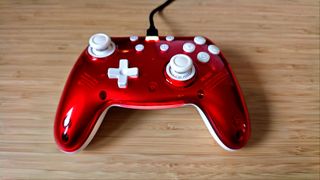 A Ruby red PB Tails Crush gaming controller sitting on a wooden desk