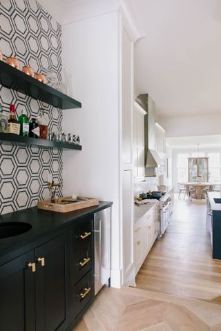 small home bar near kitchen, black cabinetry, wallpaper, open shelving, basin