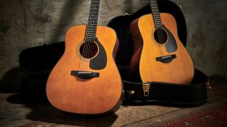 Two Yamaha acoustic guitars sitting next to a guitar case