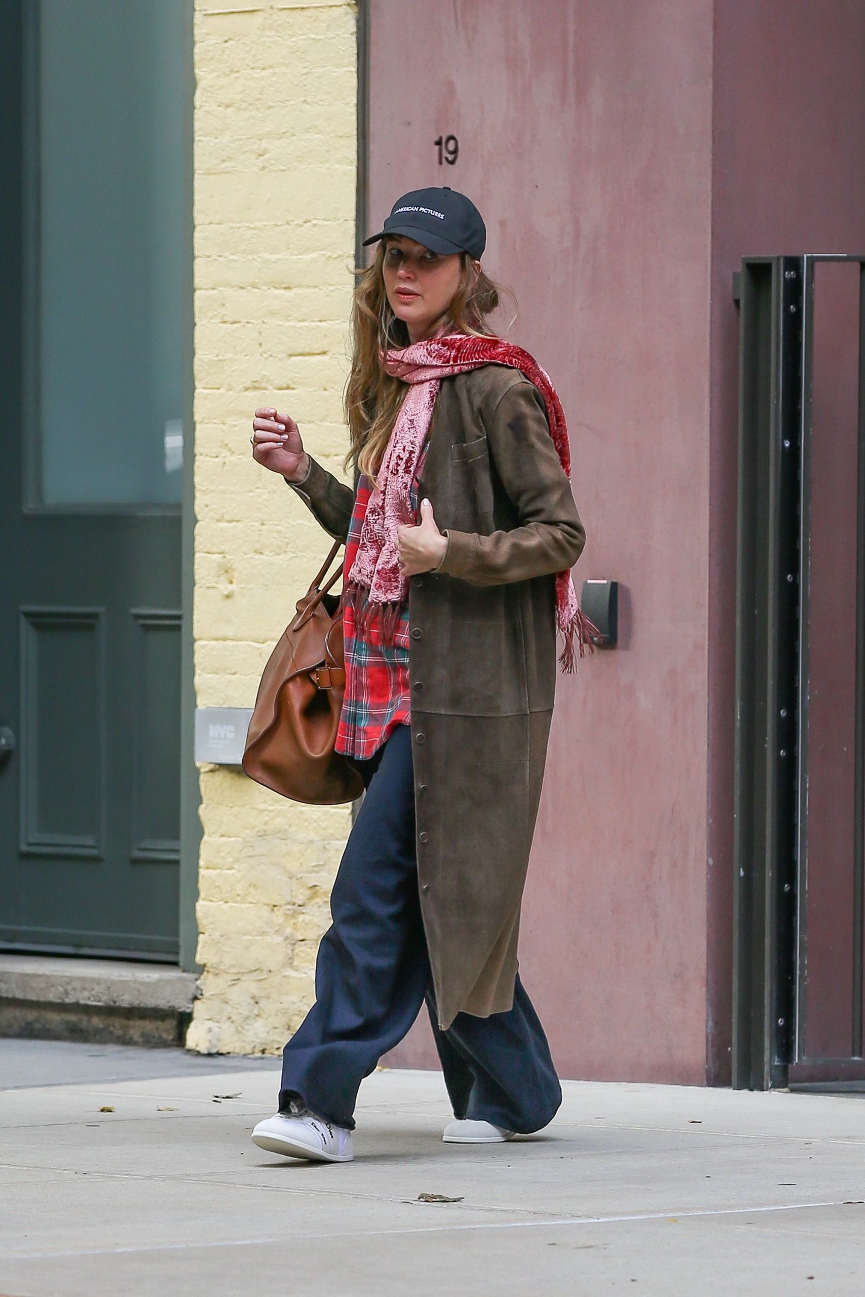 Jennifer Lawrence styled a brown suede coat with The Row Margaux Bag and white Dior sneakers