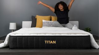 best firm mattress: Titan Plus mattress in a bedroom, with a woman smiling and stretching