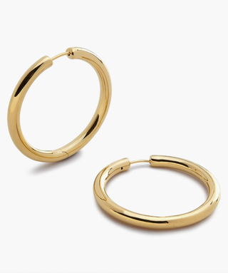 a pair of gold hoop earrings in front of a plain backdrop