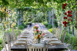 table setting beneath pergola at backyard wedding