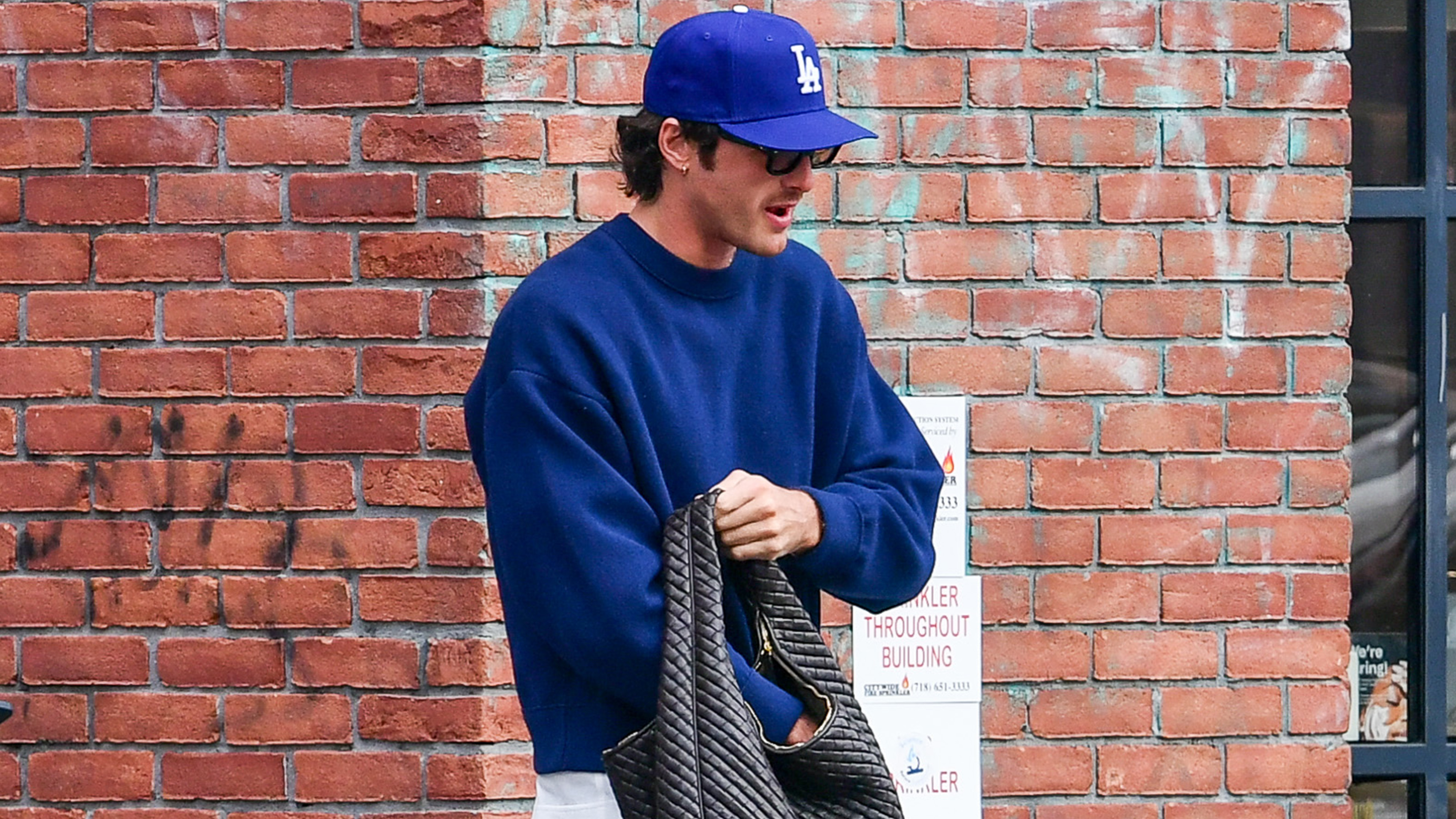 10/20/2025: Jacob Elordi is spotted carrying a large Bottega Veneta handbag in New York City. The American actor wore a blue cap, matching cropped sweatshirt, jeans, and red Nike trainers.