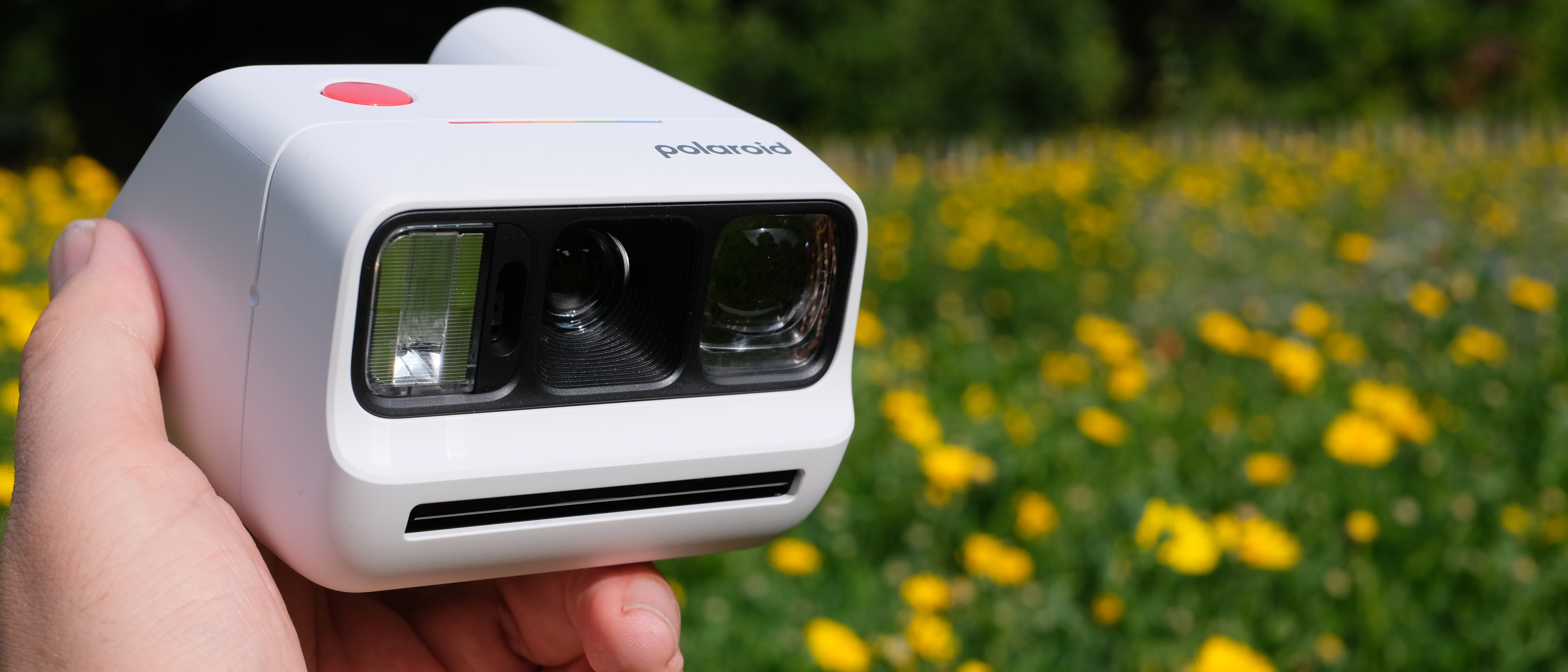 Photograph of man's hand holding Polaroid Go Gen 3 camera in white