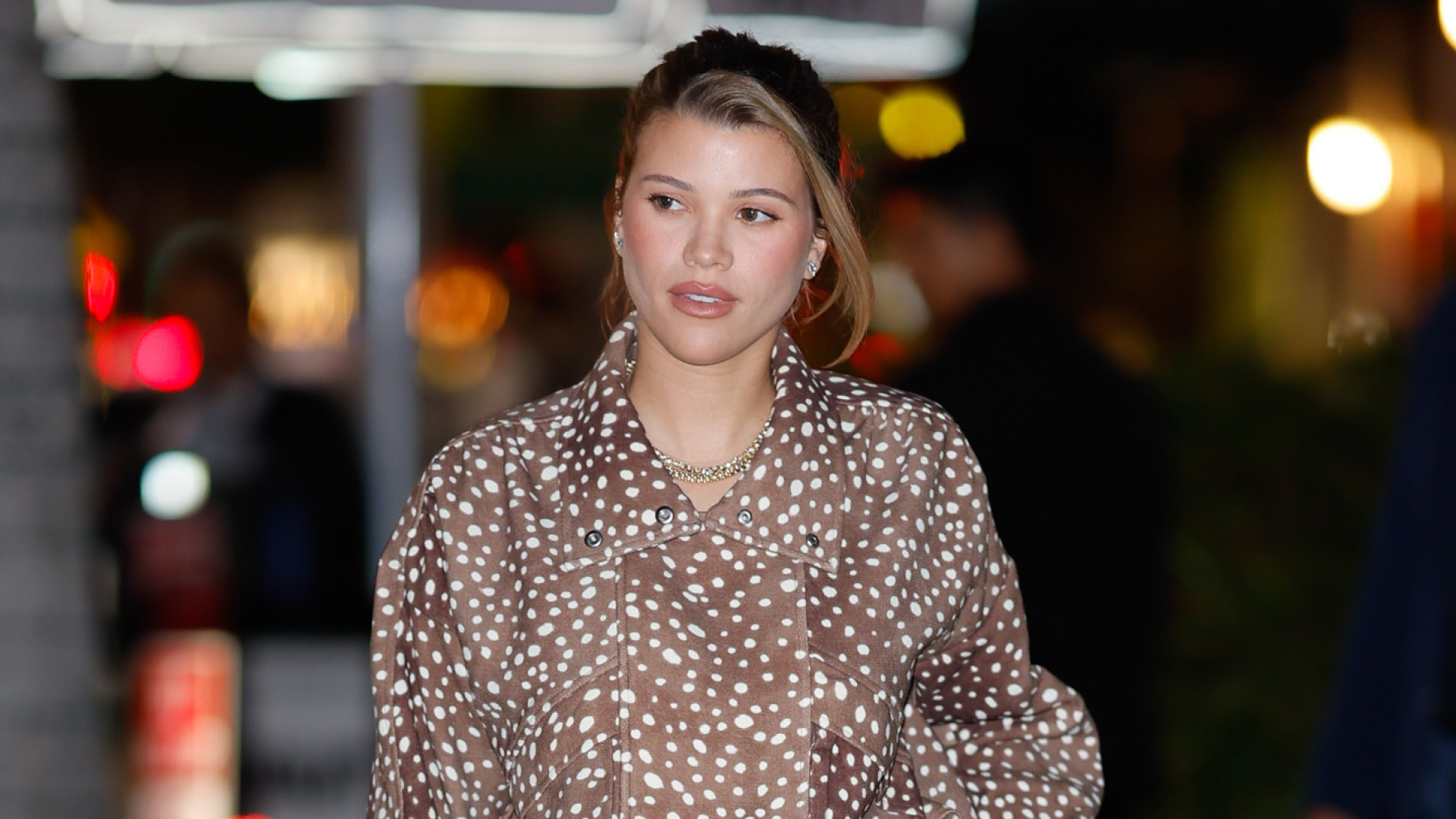 Sofia Richie wears a brown animal print jacket and has a blonde streak in her hair, which she wears tied back