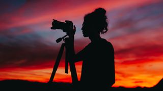 Silhouette of photographer using one of the best low-light cameras in the evening