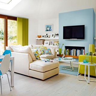 living room with white wall wooden flooring television on blue wall and white sofa