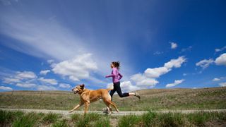 woman running a flat trail with dog