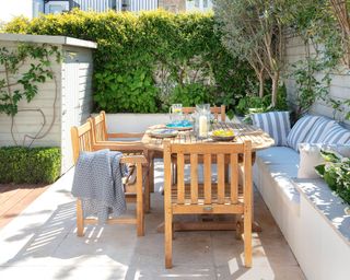 A wooden outdoor tabel and chairs on a small light colored patio