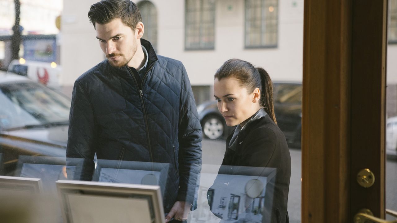 couple looking in an estate agent&#039;s window